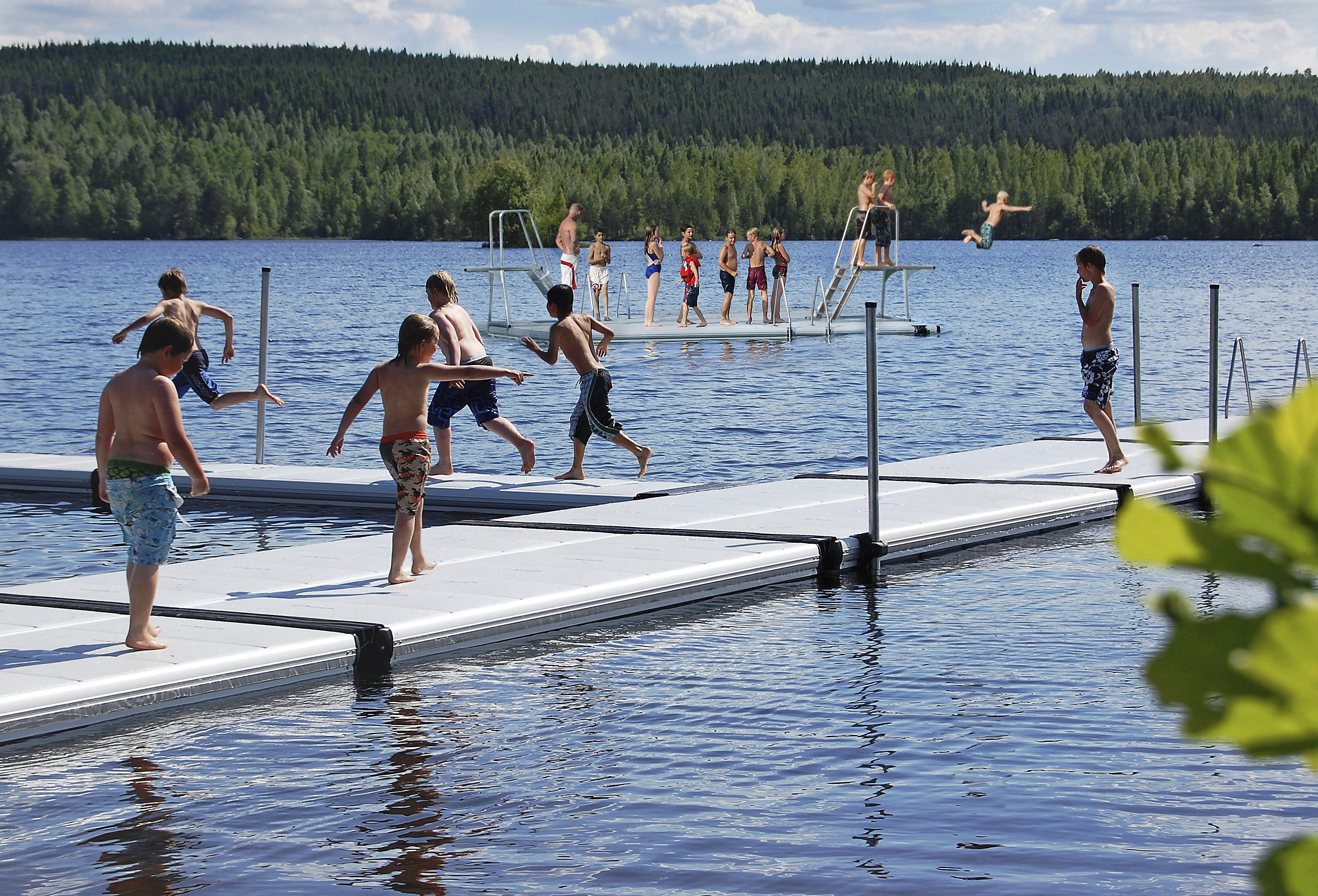 Barn  leker på en EasyFloat offentlig badbrygga i Hofors med badflotte med hopptorn