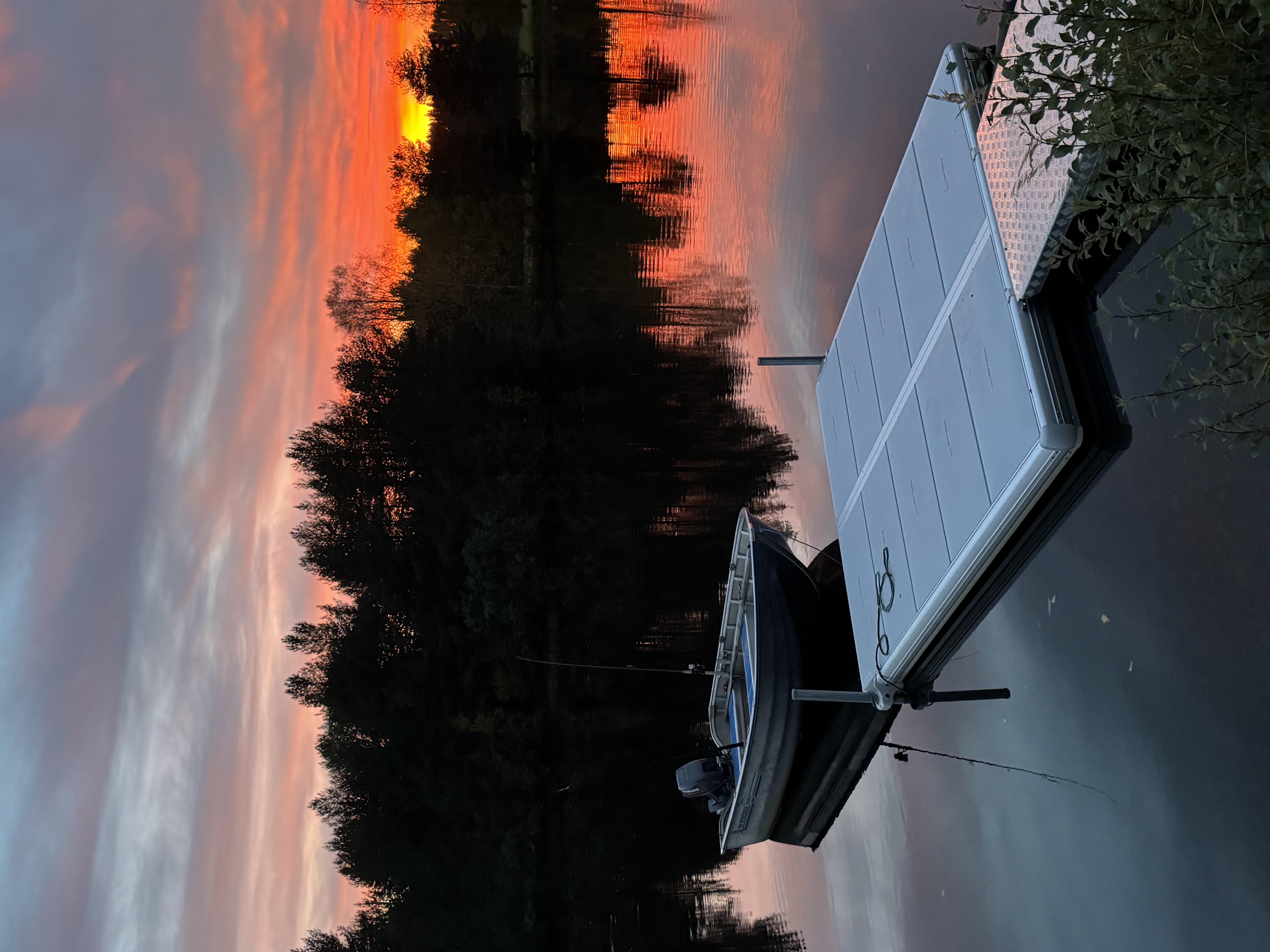 Liten EasyFloat brygga med landgång och motorbåt på stilla vatten i solnedgången